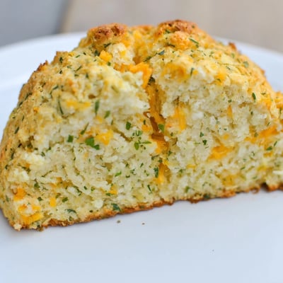 A slice of Savory Herbed Cheddar Irish Soda Bread reveals a tender, fluffy crumb studded with herbs, perfect with butter and soup.
