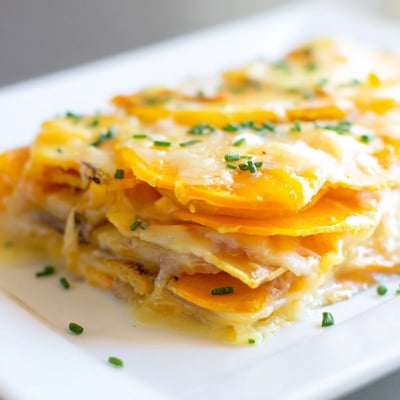 A close-up view of creamy Cheesy Sweet Potato Gratin with Caramelized Onions Delight featuring a golden-brown, cheesy crust.